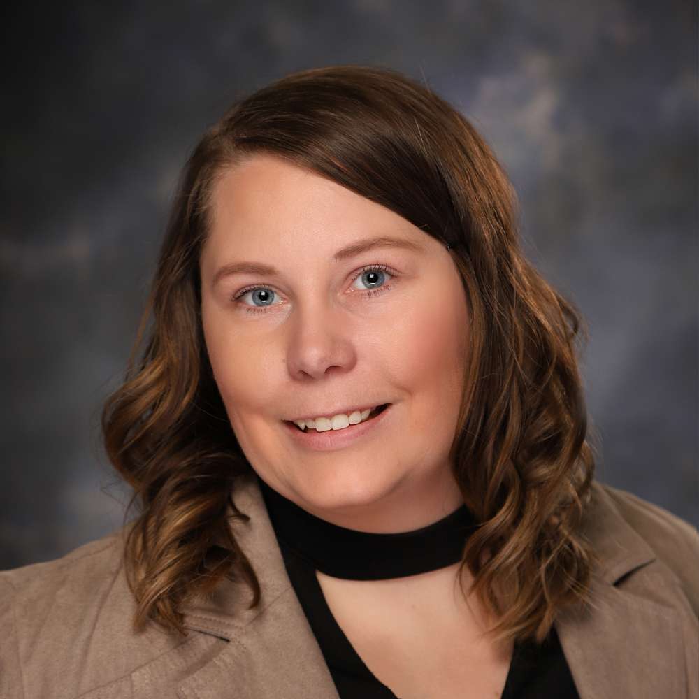 A woman in a tan jacket smiling for the camera.