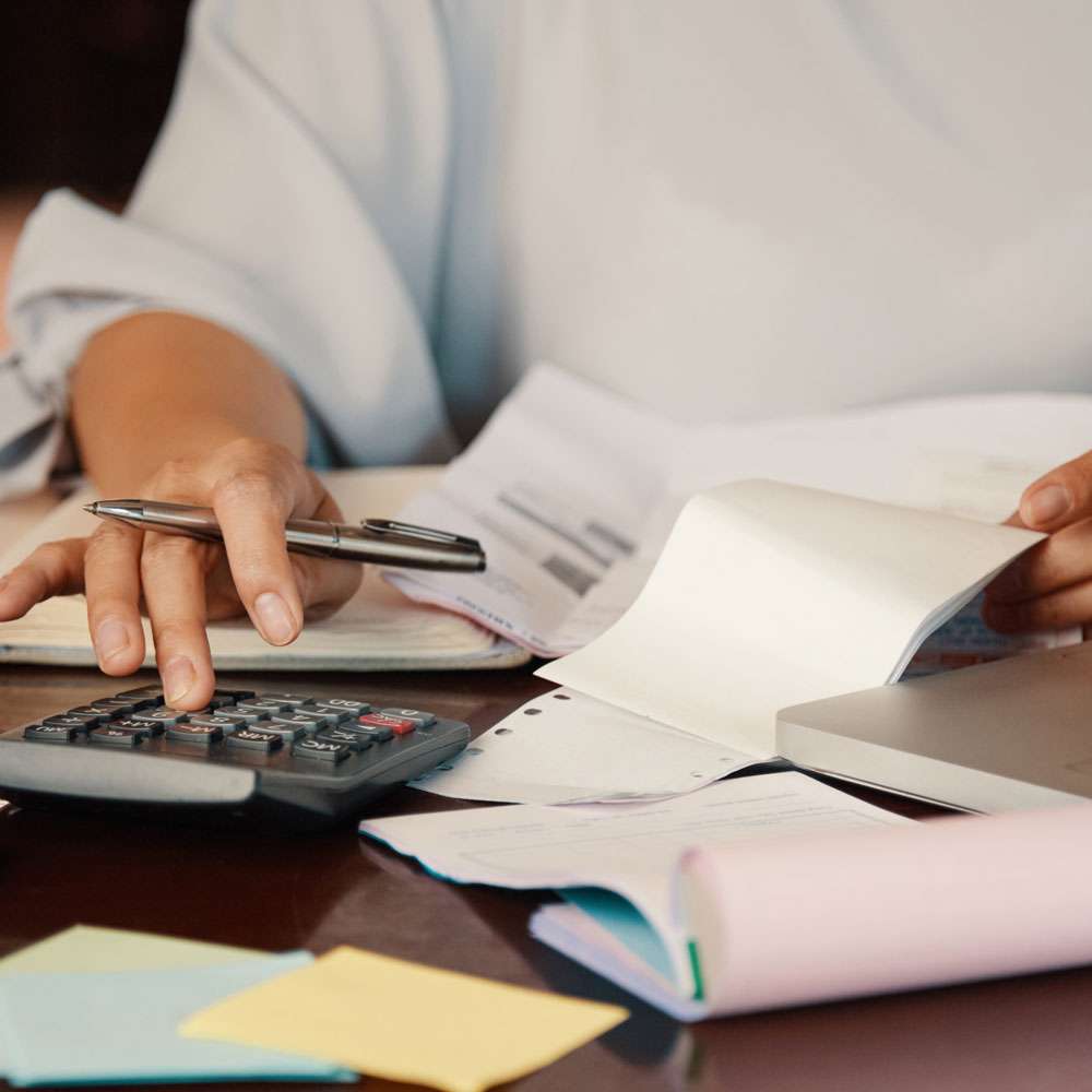 Bookkeeper adding up invoices on a calculator