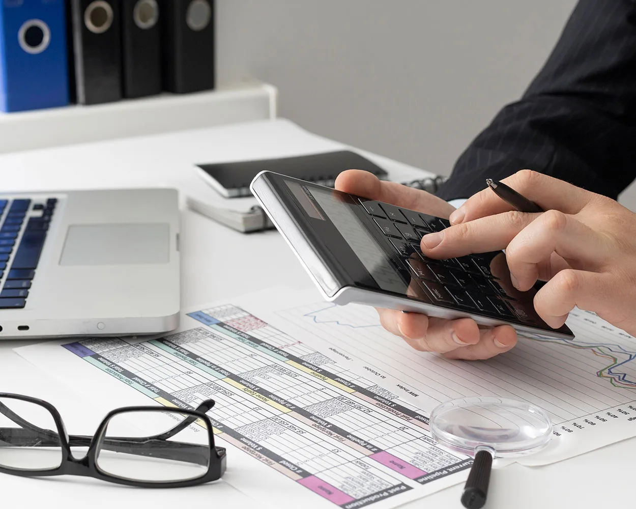 A person using a calculator on a desk for accounting purposes.